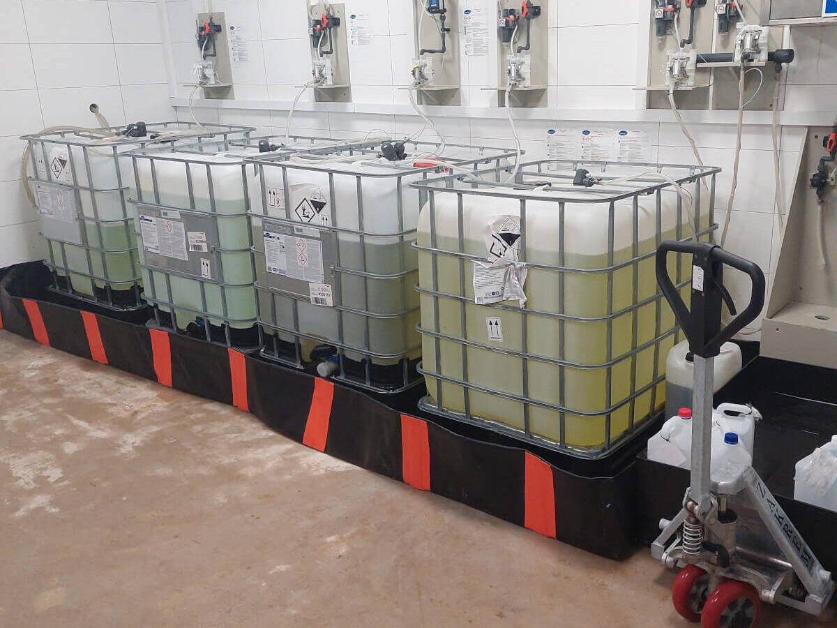 IBCs in flexible spill trays in a warehouse, with a pallet truck